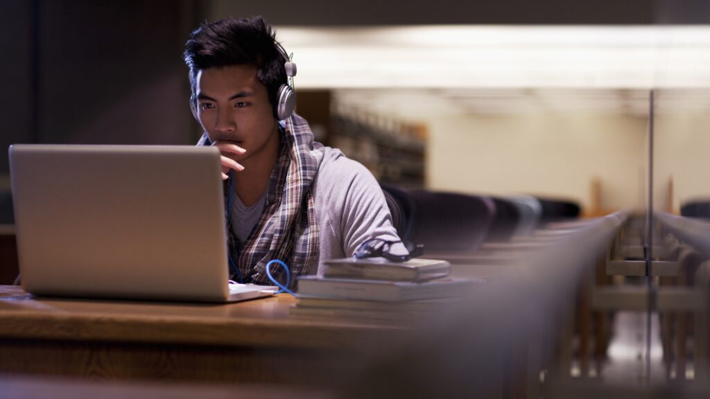 A man wearing headphones works on a laptop.
