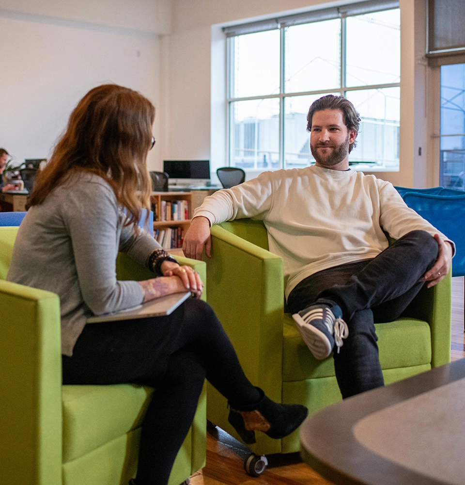 Two Noodle colleagues sit together in an open office space.