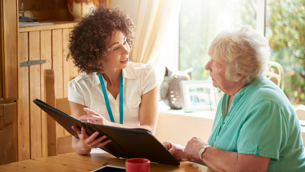 A social worker meets with a client at a sunny table.