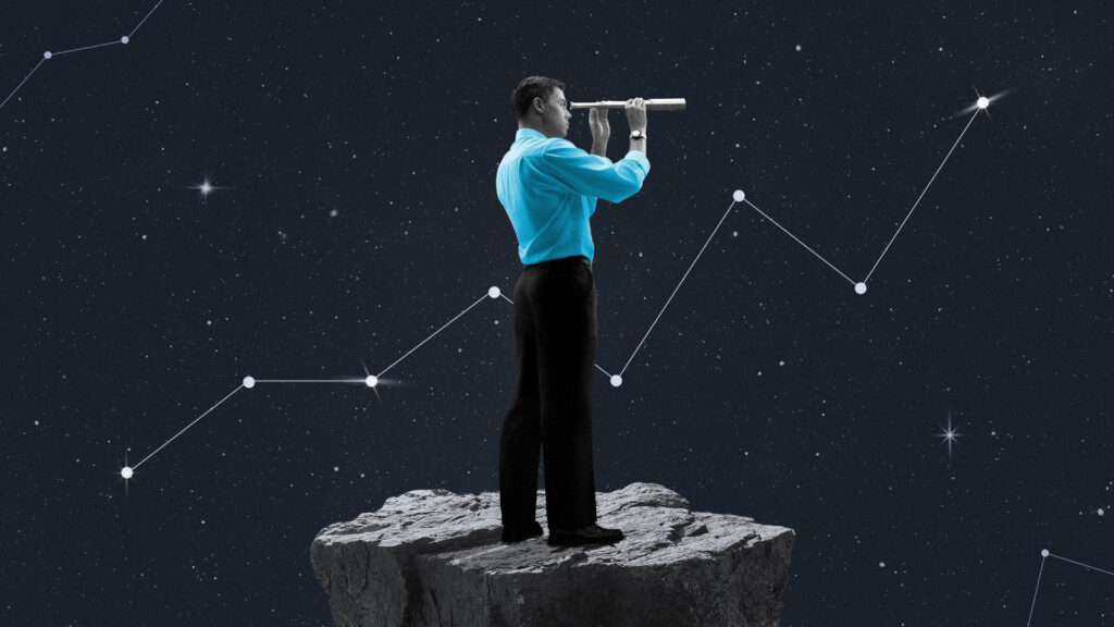 A man stands on a rock and peers through a telescope with a line graph in the background.