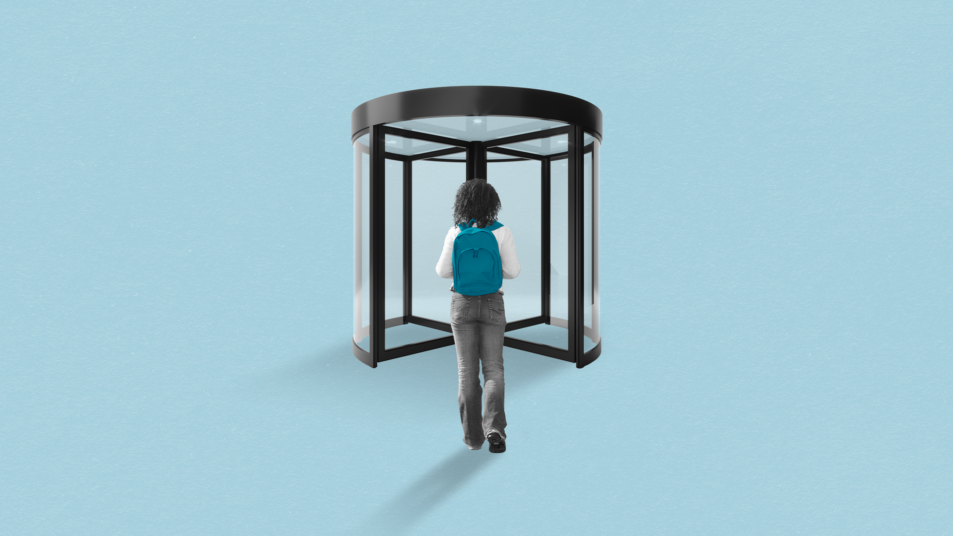 A student wearing a backpack prepares to enter a revolving door.