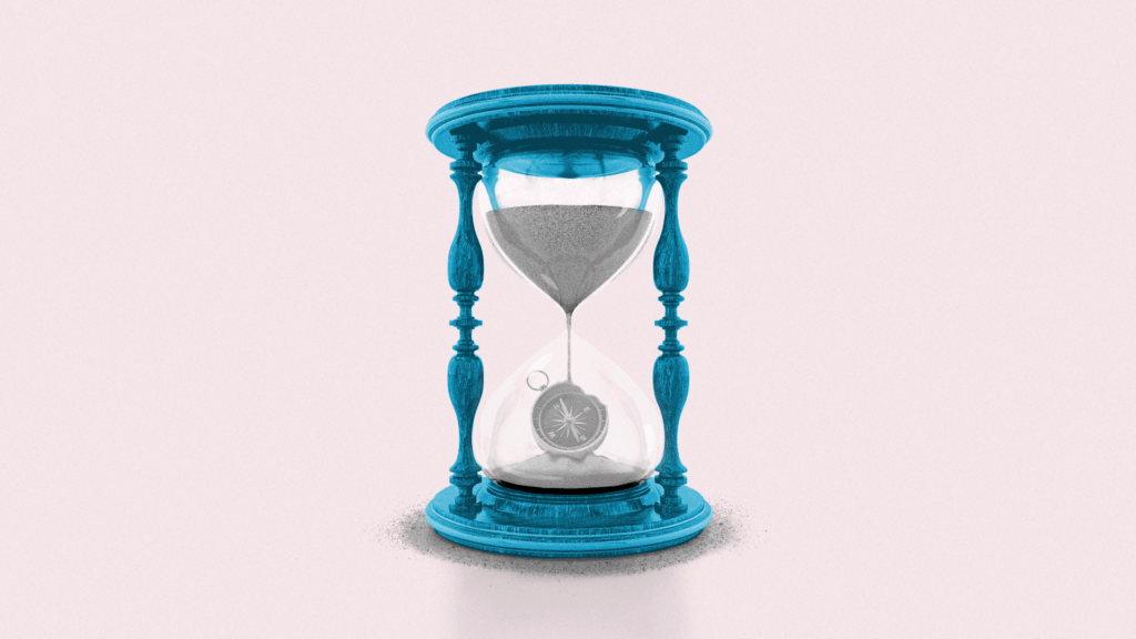 Sand filters through an hourglass, creating the shape of a compass in the lower half of the hourglass.