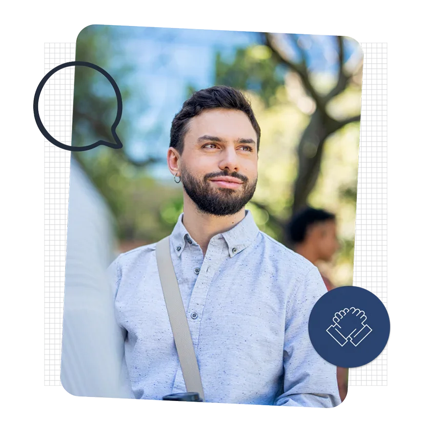 A man wearing a button-down shirt and a crossbody bag smiles off into the distance.